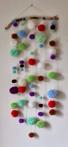 a multicolored wall hanging with pom - poms