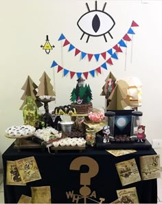 a table topped with lots of desserts and paper decorations next to a giant eye on the wall