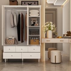 a white closet with drawers and clothes hanging on the wall next to a table, stool and mirror