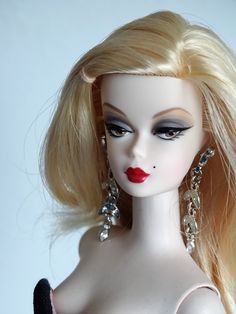 a close up of a doll with blonde hair and red lipstick on it's face