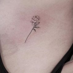 a woman's stomach with a single flower tattoo on her left side ribcage