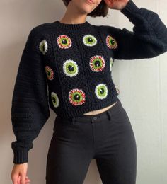 a woman wearing black pants and a knitted sweater with eyeballs on the front