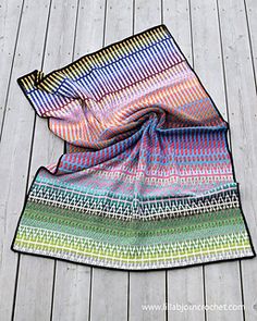 a multicolored blanket laying on top of a wooden floor