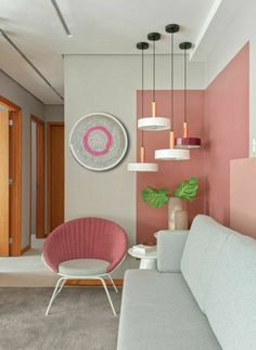 a living room with pink and white walls, two chairs and a couch in it