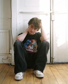 a young man sitting on the floor with his hands behind his head