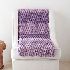 a purple knitted blanket sitting on top of a white chair