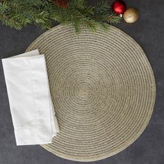 a placemat with white linens and pine needles on it next to a christmas tree branch