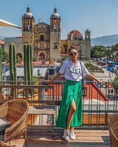 a woman standing on top of a balcony next to a cactus