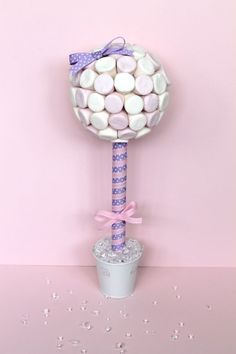 a pink and white lollipop stick on top of a cup filled with marshmallows