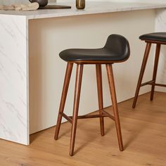 two wooden stools sitting in front of a counter