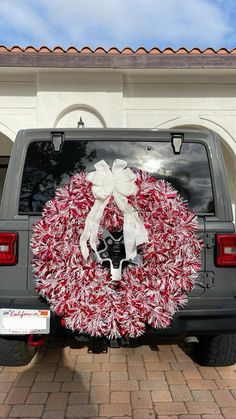 a wreath is placed on the back of a truck in front of a house with a white ribbon