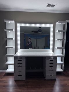 a white desk with lights on it and a person taking a photo in the mirror