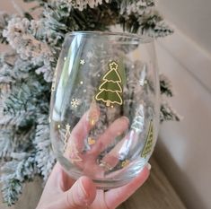 a person holding up a wine glass with christmas decorations on the bottom and gold lettering