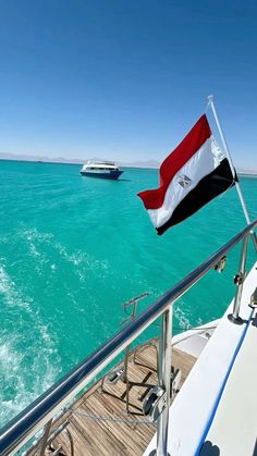 the flag of egypt is flying on top of a boat in the blue water with another boat behind it