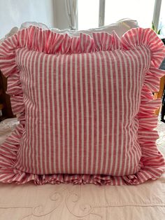 a red and white striped pillow sitting on top of a bed