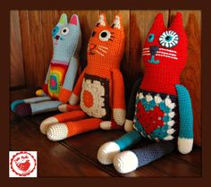 three crocheted cats sitting next to each other on top of a wooden table