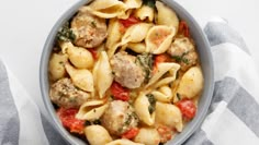 a bowl filled with pasta and meatballs on top of a striped cloth next to a fork