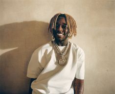 a man with dreadlocks and a white t - shirt is smiling at the camera