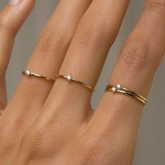 a woman's hand with two gold rings on top of her finger and one diamond ring in the middle