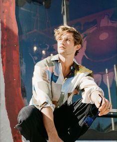 a young man sitting on top of a skateboard next to a red and blue wall