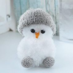 a small white stuffed animal wearing a knitted hat and beanie sitting on a table