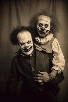 two creepy clowns posing for the camera with one holding his arm around the other