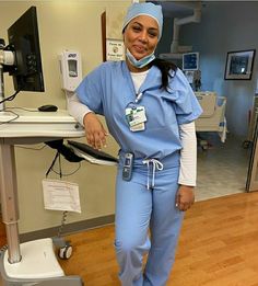 a woman in scrubs standing next to a monitor