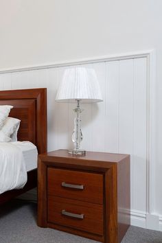 a bed sitting next to a night stand with a lamp on it's side