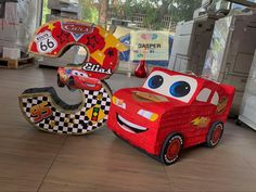 two cars made out of cardboard are sitting on the floor in front of each other