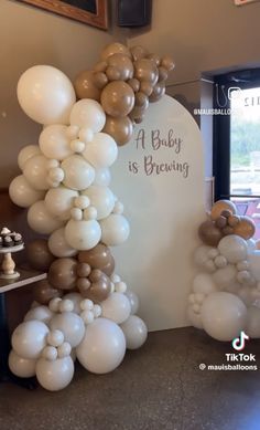 balloons are stacked on top of each other in the shape of an arch that reads a baby is brewing