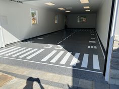 an empty parking garage with white lines painted on the floor and doors open to let in light