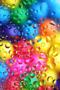 colorful drops of water on the surface of a rainbow colored glass window with multicolored bubbles