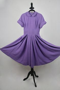 "1950s hand made dress. Purple rayon, plain weave fabric. The weight of the fabric would make a great swing dress. Peter Pan collar and cuffed cap sleeves. Wide, 3\" waist. Waist, collar, and cuffs have stiffening in them. Full skirt is box pleated and has reverse, decorative seaming. (see next to last photo although the color is off in this photo) 3.5\" hem. Fastens in the back with a short metal zipper and another one in the side. Freshly laundered. Excellent condition. There is one small dark Retro Solid A-line Vintage Dress, Solid Color A-line Retro Vintage Dress, Solid Color Retro A-line Vintage Dress, 1950s Style Lined Short Sleeve Dresses, 1950s Style Short Sleeve Lined Dress, Fitted Dresses With Peter Pan Collar For Vintage Fashion, Vintage Fashion Fitted Dress With Peter Pan Collar, Fitted Dress With Peter Pan Collar In Vintage Style, Peter Pan Collar Vintage Style Fitted Dress