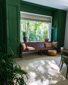 a living room with green walls and wooden furniture in the corner, along with potted plants