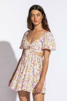 STYLE INFORMATION: We're ready for sunshine and the Valerie Wildflower Floral Print Puff Sleeve Cutout Mini Dress! Wildflower floral print woven fabric shapes this dress that has a deep V-neckline, center ring, a slightly fitted bodice, and short puff sleeves with elastic at the cuffs. The open back wraps around to the sides (with ties) to create a cutout effect above the skater mini skirt. The back secures with a tie sash and elastic above the waist for a perfect fit. DETAILS & CARE: Rayon/Poly Flirty V-neck Floral Dress For Summer, Flirty V-neck Floral Summer Dress, Flirty V-neck Floral Dress For Vacation, Flirty V-neck Floral Dress For Beach, Cutout Mini Dress, Boho Pink, Fit Details, Pink Floral Dress, Pink Boho