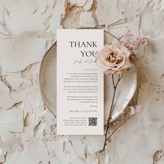 a thank card sitting on top of a plate next to a pink flower and leaves