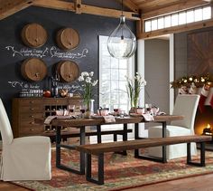 a dining room table with wine glasses on the wall and chalk writing on the wall behind it