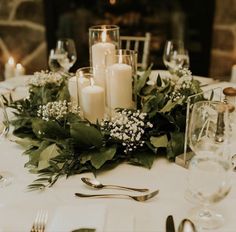 the table is set with candles and greenery