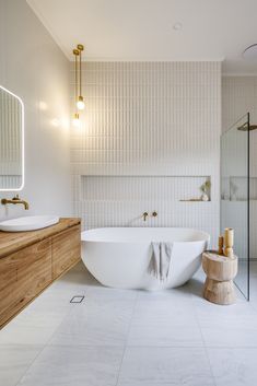 a large white bath tub sitting next to a wooden counter top under a mirror in a bathroom