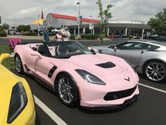 two cars parked next to each other in a parking lot with people looking at them