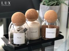 three glass jars filled with different types of coffee beans and spices on a black tray