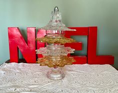 a three tiered glass cake stand sitting on top of a doily covered table