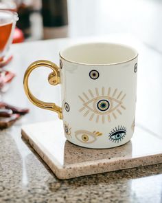 a white and gold coffee cup sitting on top of a marble coaster