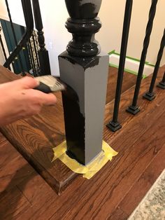 a person is painting the bottom of a stair banister with black paint on it