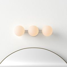 two round lights are mounted on the wall above a mirror in a room with white walls