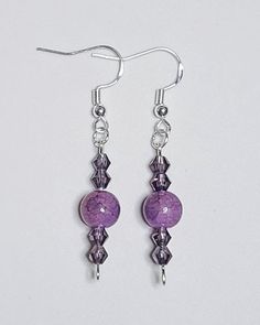 purple glass beaded earrings with silver earwires on a white background, close up