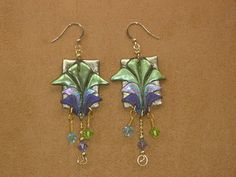 a pair of earrings with green and purple flowers