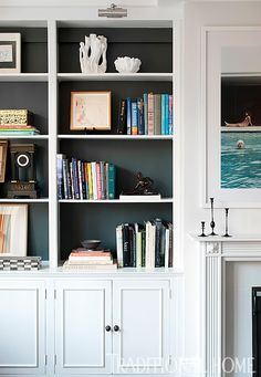 a white bookcase filled with books next to a fire place