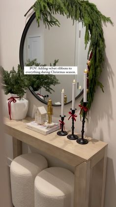 a mirror sitting above a wooden table with candles and decorations on it, next to two stools