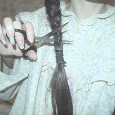 a woman is cutting her hair with scissors